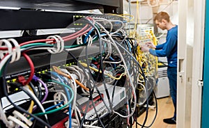 Network engineer working in server room. Connecting network cables to switches