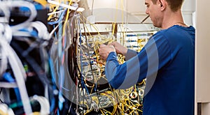 Network engineer working in server room. Connecting network cables to switches