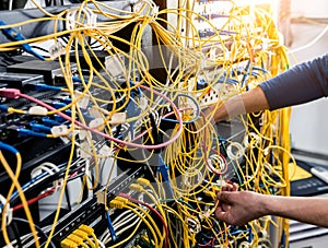 Network engineer working in server room. Connecting network cables to switches