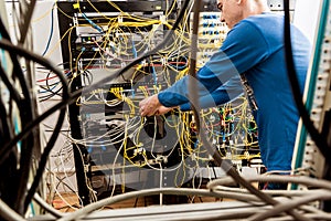 Network engineer working in server room. Connecting network cables to switches