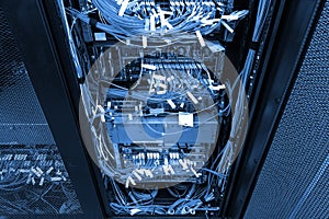 Network hub and patch UTP LAN cables in rack cabinet with dark cold blue toning