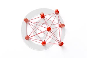 Network with red pins and string,  linked together with string on a white background suggesting a network of connections