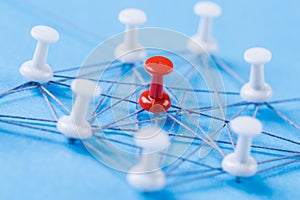 Network with red and white pins and string, An arrangement of colorful pins linked together with string on a blue background