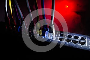 Network switch and ethernet cables, symbol of global communications. Colored network cables on dark background with lights and smo