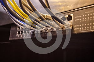 Network switch and ethernet cables, symbol of global communications. Colored network cables on dark background with lights and smo