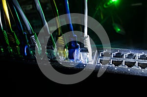 Network switch and ethernet cables, symbol of global communications. Colored network cables on dark background with lights and smo