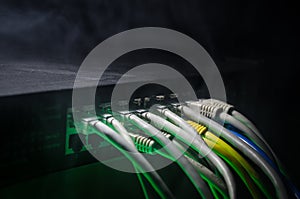 Network switch and ethernet cables, symbol of global communications. Colored network cables on dark background with lights and smo