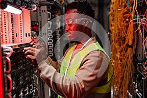 Network technician inspecting servers in data center red neon light