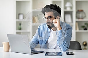 Networking Concept. Focused Indian Man Working With Laptop At Home Office