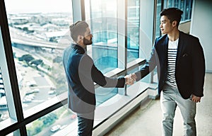 Networking, a powerful business tool. two young businessmen shaking hands in a modern office.