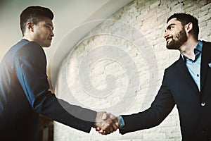 The networking pros. two young businessmen shaking hands in a modern office.