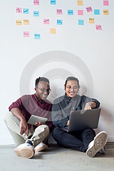 Networking and sharing connections. Full length shot of two young businessmen sitting in the floor and using their