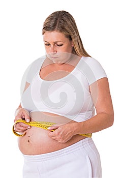 Pregnant woman measures her waist circumference with a tape measure photo