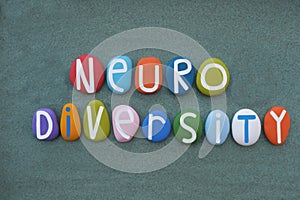Neurodiversity word composed with multi colored stone letters over green sand photo