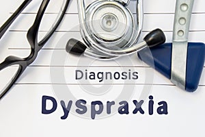 Neurological diagnosis of Dyspraxia. Neurological hammer, stethoscope and doctor`s glasses lie on doctor workplace on sheet of not