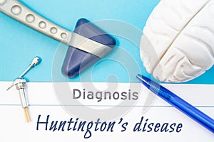 Neurological diagnosis of Huntington`s disease. Neurological hammer, human brain figure, tools for sensitivity testing are on tabl photo