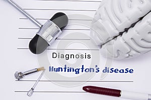 Neurological diagnosis of Huntington`s disease. Neurological hammer, human brain figure, tools for sensitivity testing are on tabl