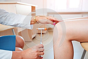 Neurological examination. The neurologist testing reflexes on a female patient