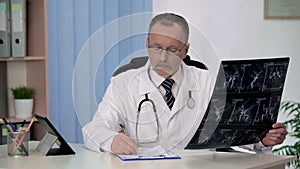 Neurologist checking angiography of blood vessels, writing prescription in form