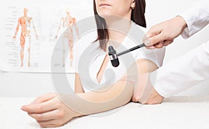 A neurologist doctor checks the biceps reflex in a girl patient with a neurological hammer, areflexia photo