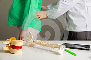 A neurologist doctor examines a pregnant woman who has back pain from muscle strain during pregnancy. Load on the spine