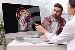 Neurologist showing brain scan to sad man in clinic