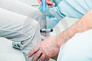 The neurologist testing knee reflex on a female patient using a hammer. Neurological physical examination. Selective focus, close