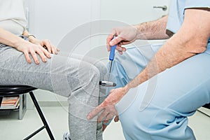 The neurologist testing knee reflex on a female patient using a hammer. Neurological physical examination. Selective focus, close