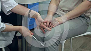 Neurologist testing reflexes on female patient using hammer