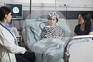 Neurology specialist measuring neurologic disease evolution of sick kid sitting in pediatric healthcare facility photo