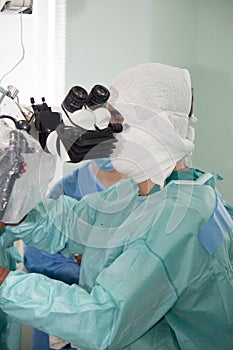 A neurosurgeon doctor looks into a microscope during an operation. Neurosurgery and microsurgery.