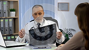 Neurosurgeon observing brain x-ray, going to tell patient about serious illness