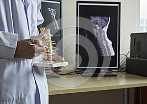 A neurosurgeon pointing at cervical spine model