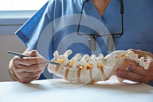 A neurosurgeon pointing at lumbar vertebra model