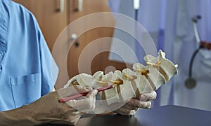 A neurosurgeon pointing at lumbar vertebra model in medical off