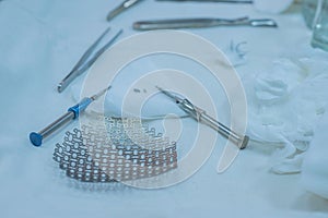 Neurosurgical instruments, including a titanium plate for implantation in the skull, are on the sterile operating table of a nurse