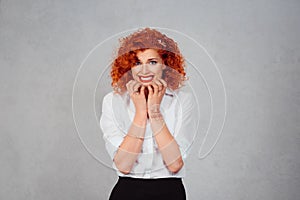 Neurotic. Scared shocked redhead curly woman isolated on gray background