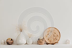 Neutral vases on a white shelf against rough stucco of a gray wall. Home decor