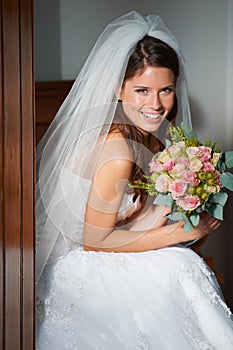 Never a bride so beautiful. Portrait of a beautiful young bride sitting on a pew holding a bouquet.