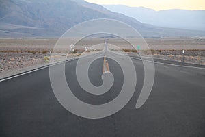 The never ending road during the dusk of a sunset in the Death Valley desert