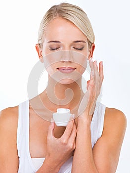 Never forget to moisturise. A beautiful young woman applying moisturiser to her face. photo