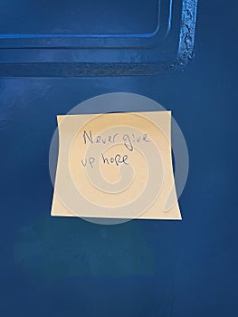 Never give up hope mesage written in a note on a blue mailbox