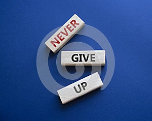 Never give up symbol. Concept words Never give up on wooden blocks. Beautiful deep blue green background. Business and Never give