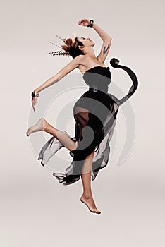 Never miss a chance to dance. A young woman in a chiffon dress dancing while isolated on a plain background.