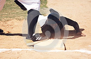 We never outgrow playing in the dirt. a young man reaching base during a baseball match.