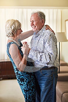 Never stop dancing, never stop romancing. a happy senior couple dancing together at home.