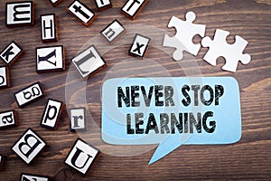 Never stop learning concept. Speech Bubble on a dark textured wooden background photo