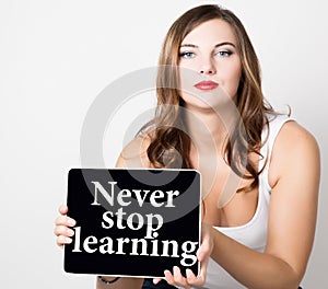 Never stop learning written on virtual screen. beautiful woman with bare shoulders holding pc tablet. technology