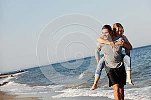 Never too old for a piggyback. a young man giving his girlfriend a piggyback by the sea.