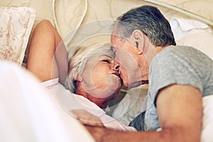 Never too old for romance. a senior couple being affectionate in their bedroom.